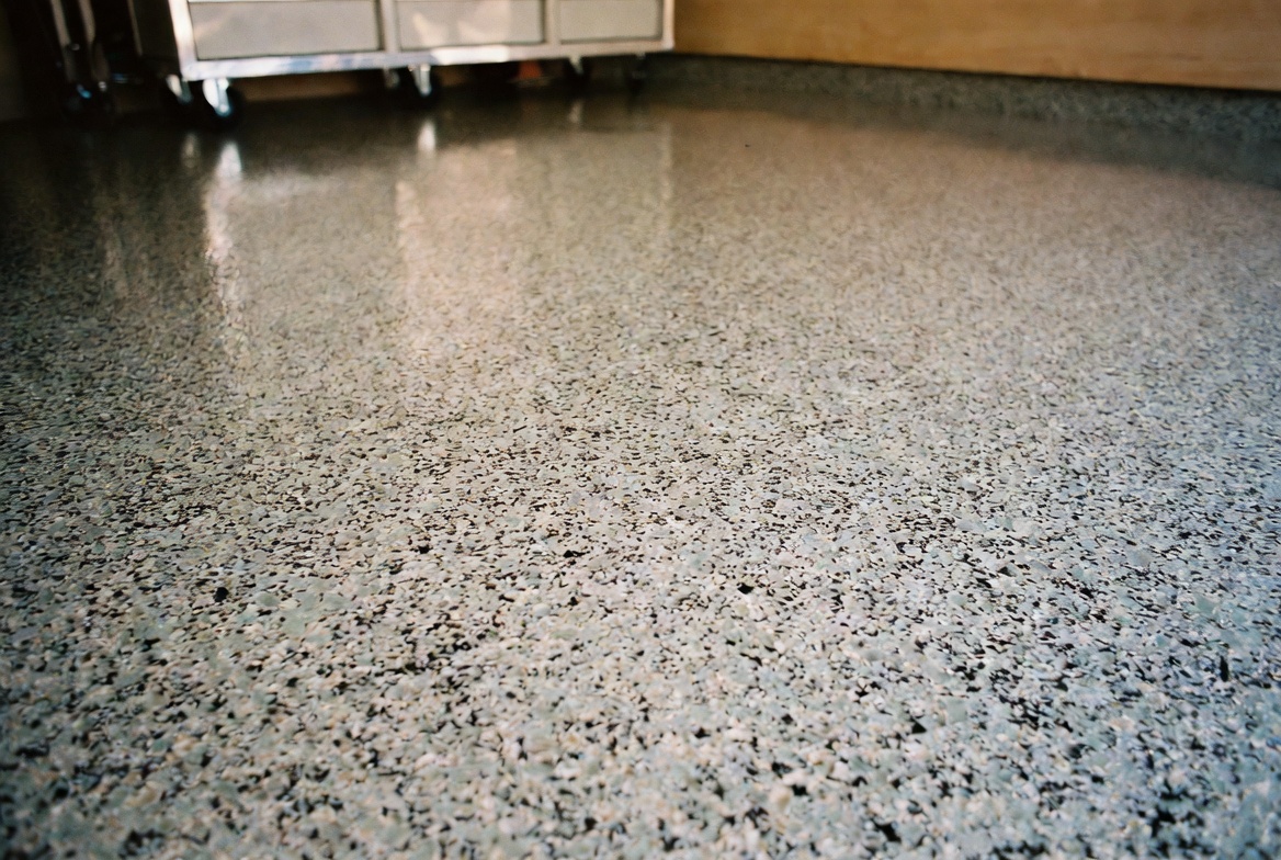 Workshop close-up of a freshly installed granite-flake epoxy floor with tool chest